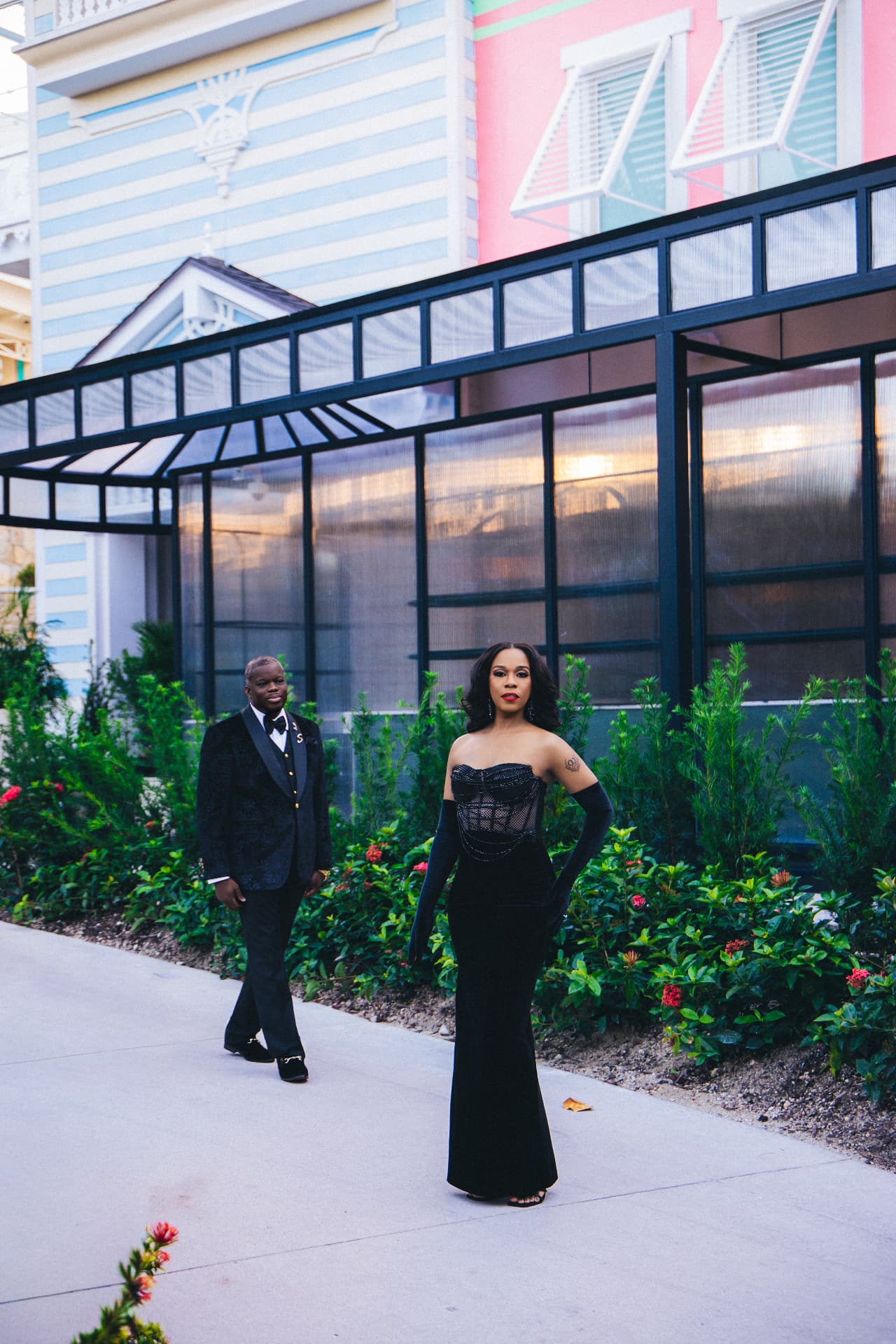 Fiancée posing on a resort walkway as her partner looks on