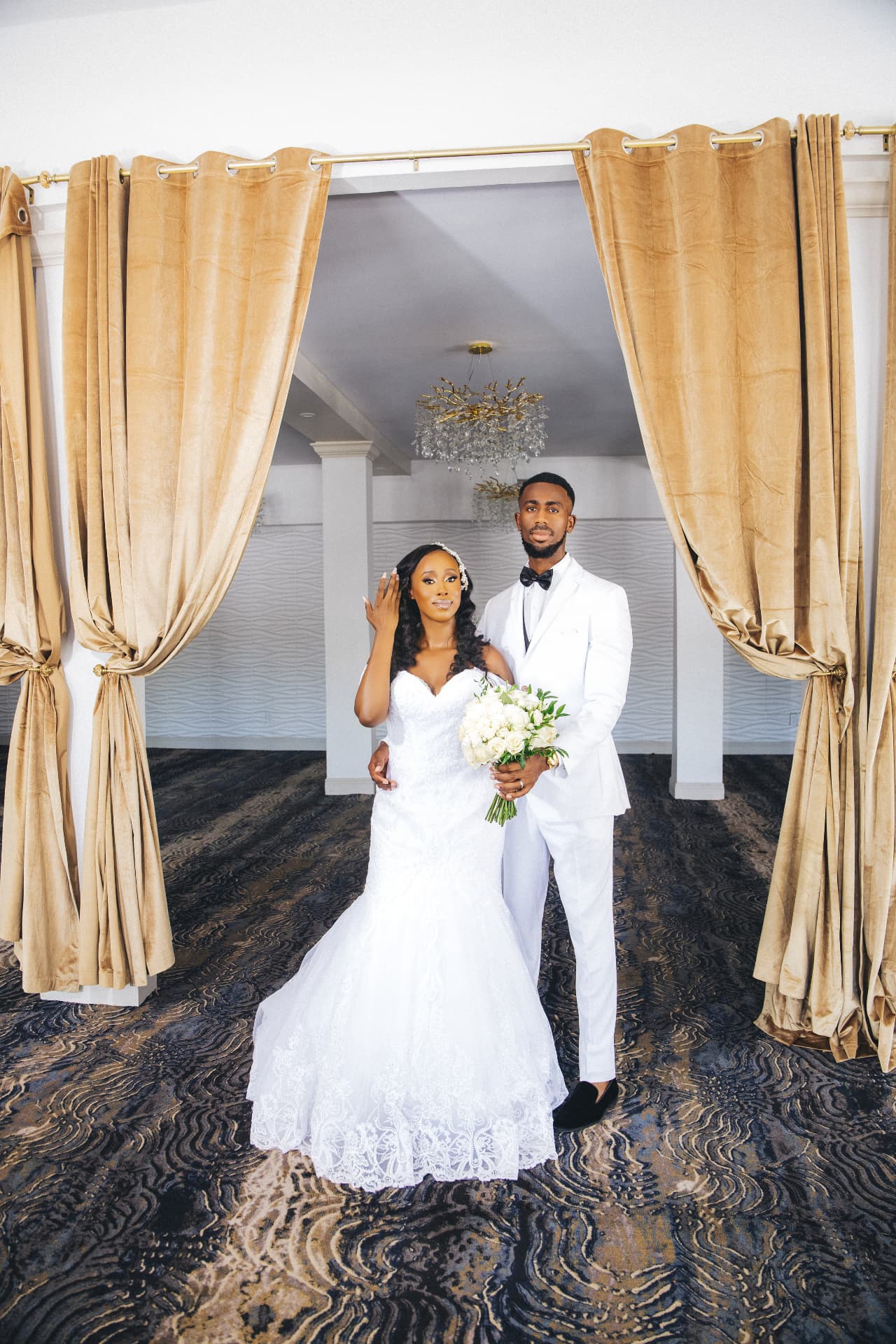 Bride and groom framed by golden velvet drapes