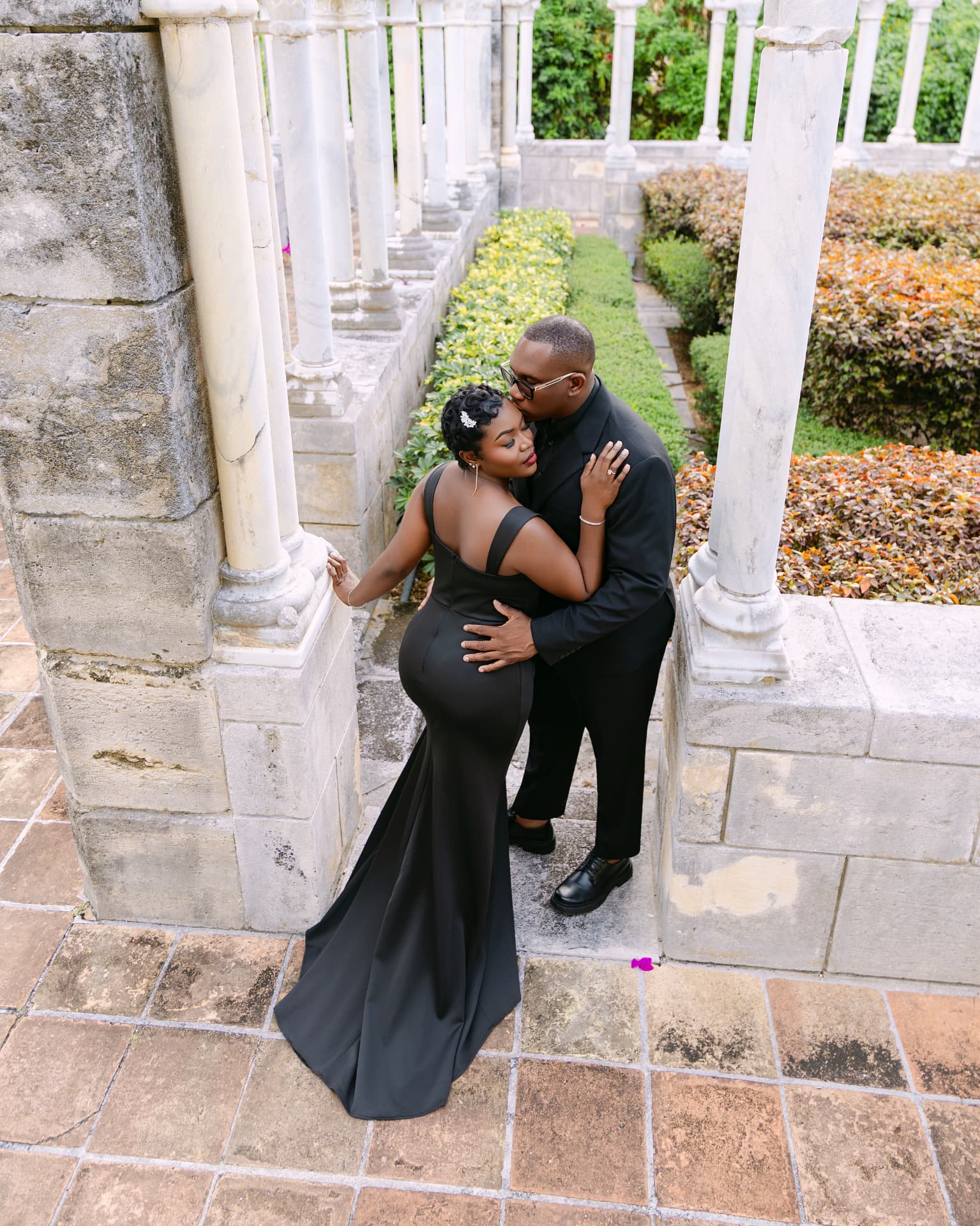 Couple embracing between cloister columns above a garden