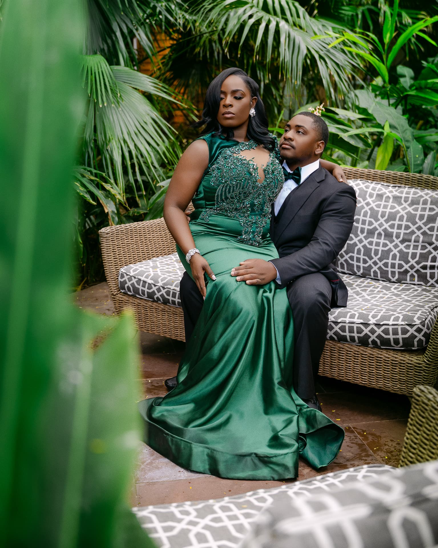 Couple seated among tropical palms, bride in emerald satin