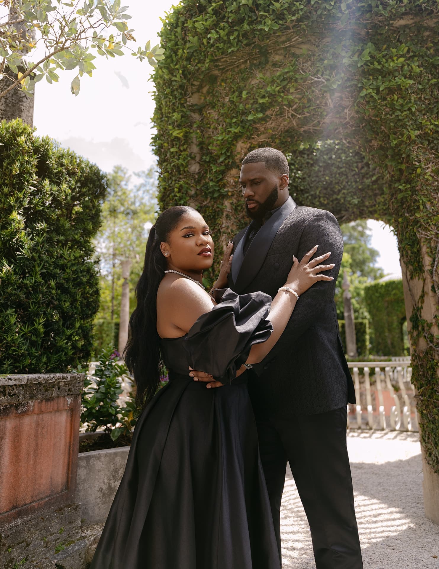 Couple embracing under an ivy-covered garden arch