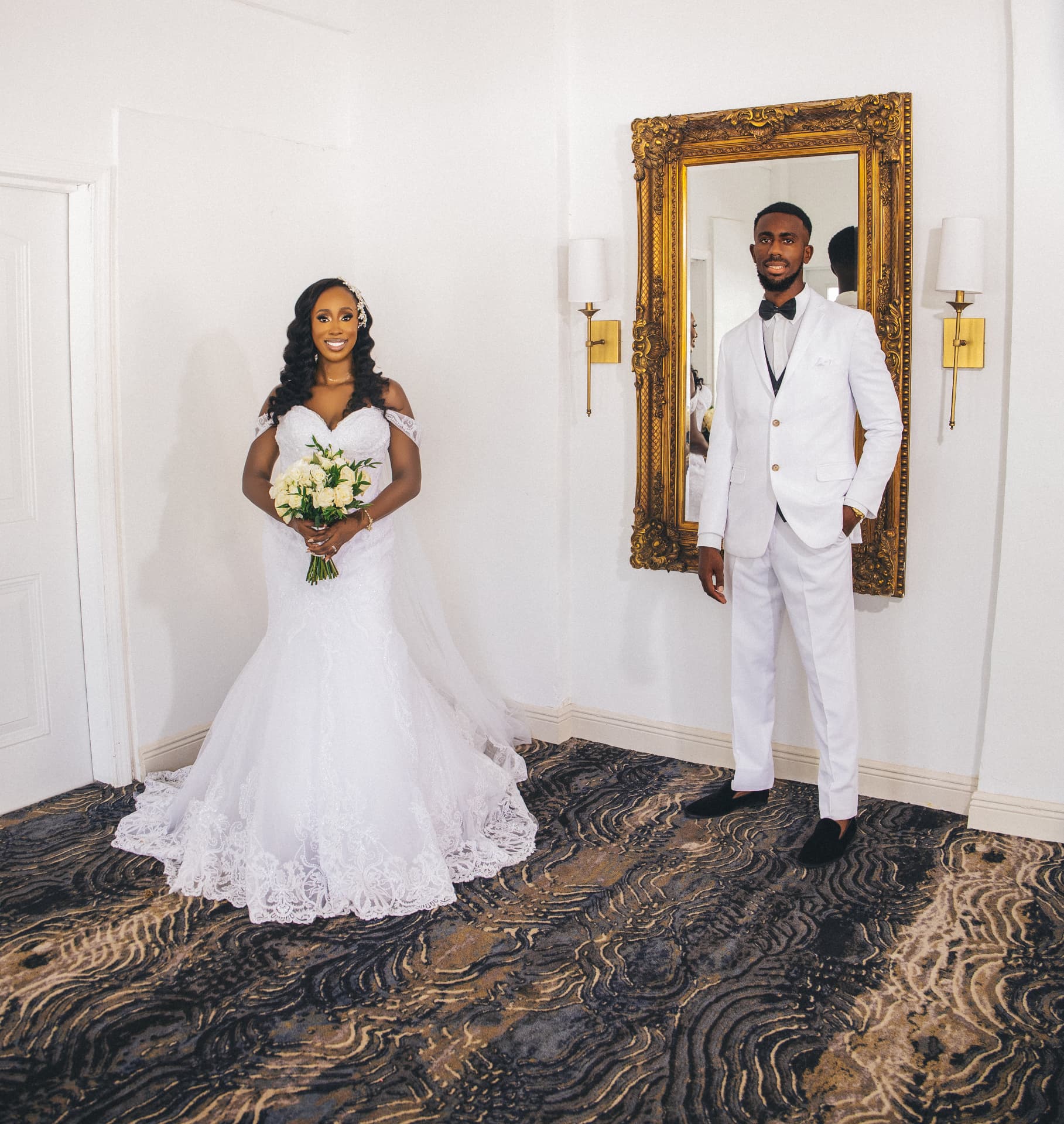Bride with bouquet beside her groom near a gilded mirror