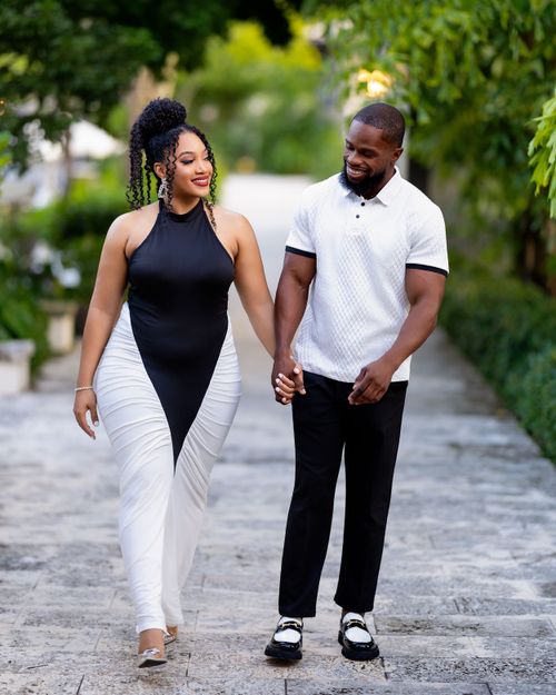 Couple walking hand in hand down a stone garden path