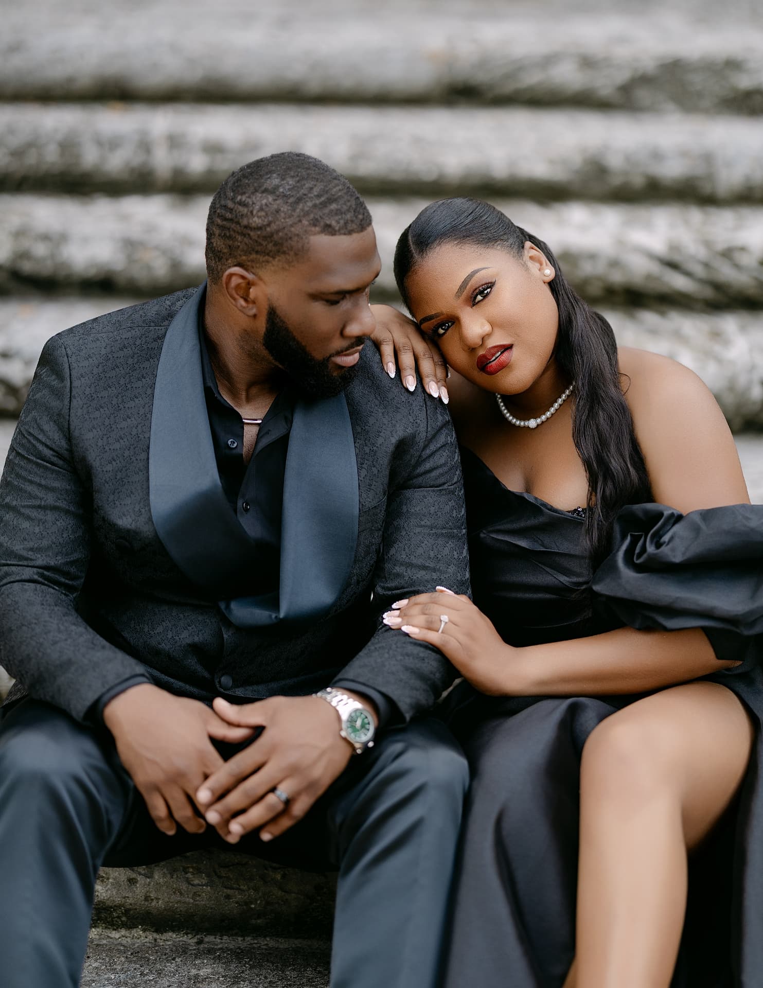 Couple in black formalwear seated on stone steps