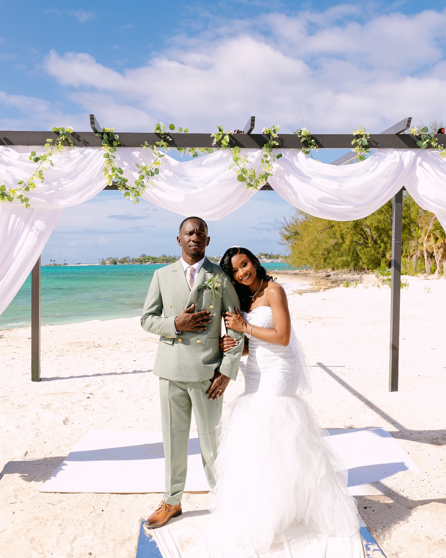 Beach ceremony portrait beneath a draped arbor