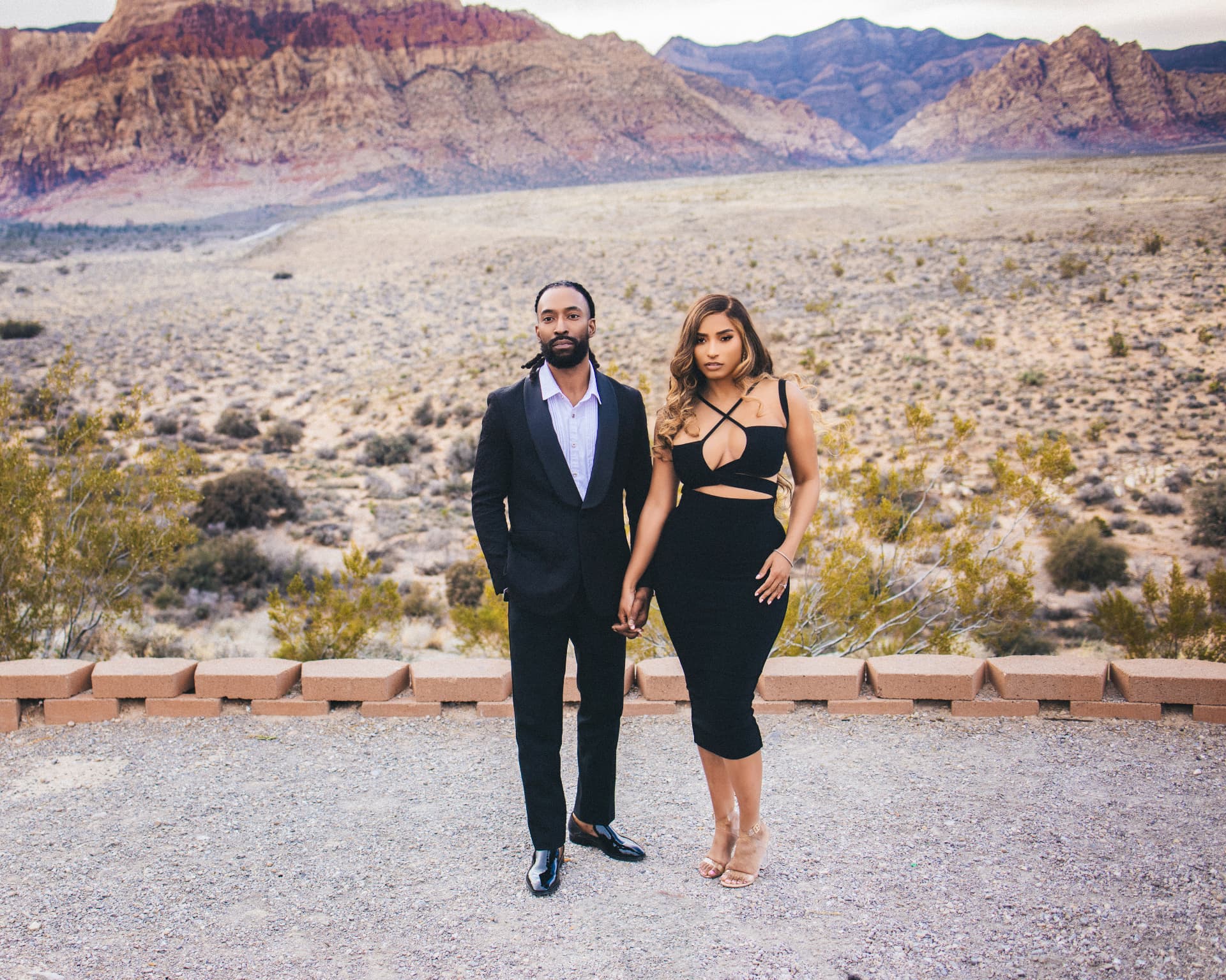 Couple holding hands in front of red rock desert mountains