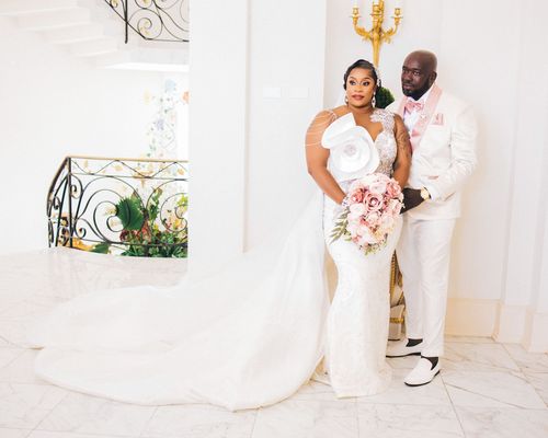 Couple posing on a marble staircase with a blush bouquet