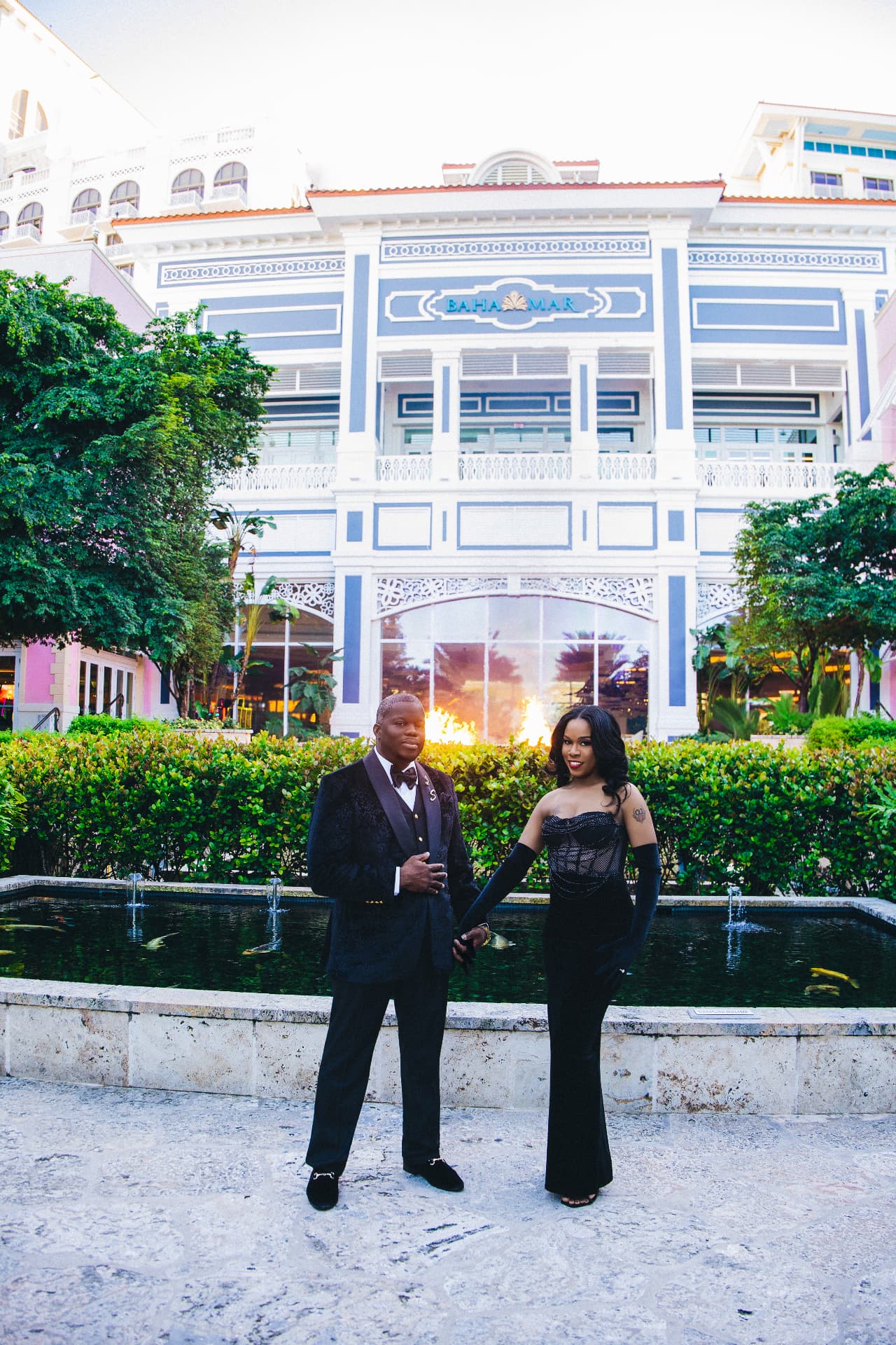 Couple in black tie before a grand resort fountain at dusk