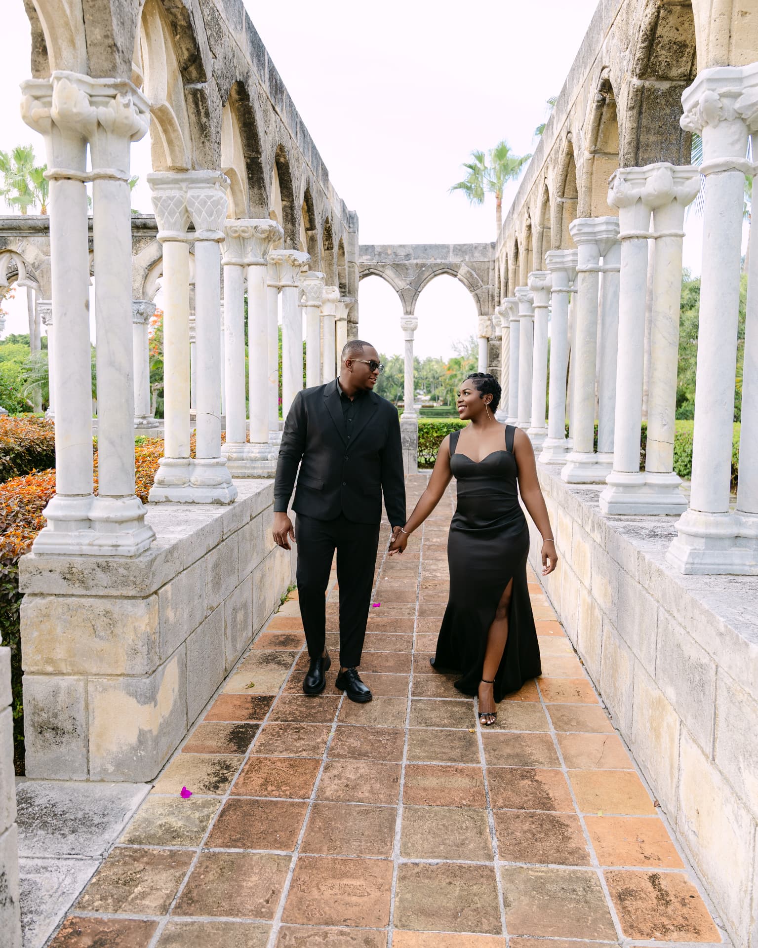 Couple walking hand in hand through a marble colonnade