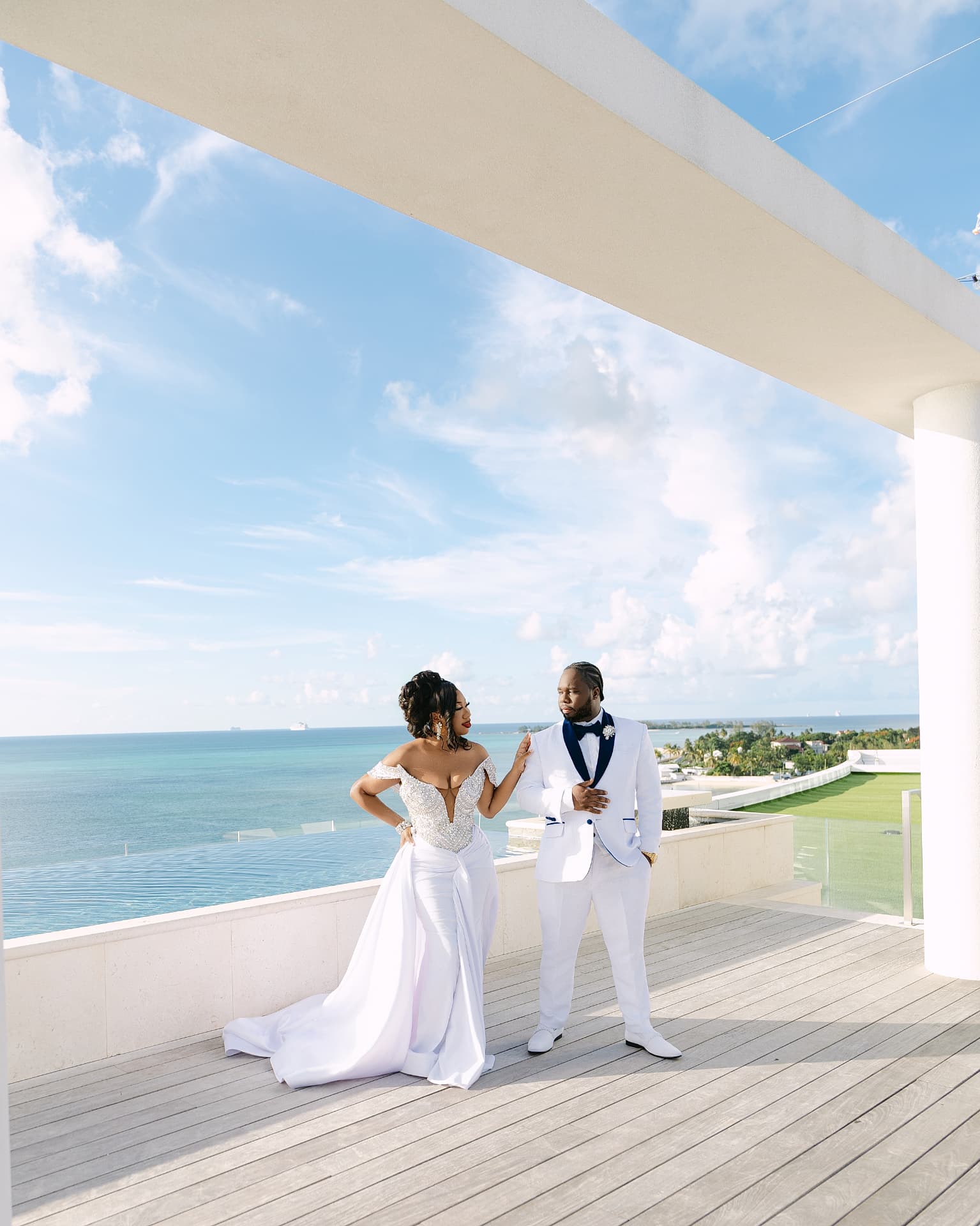 Bride and groom on an oceanfront terrace in white formalwear