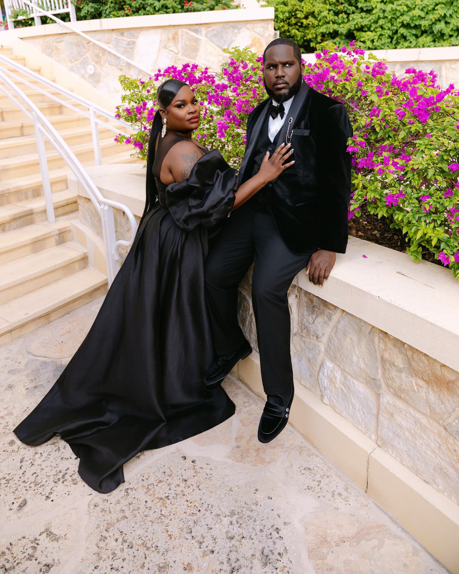 Couple in black tie on stone steps beside bougainvillea
