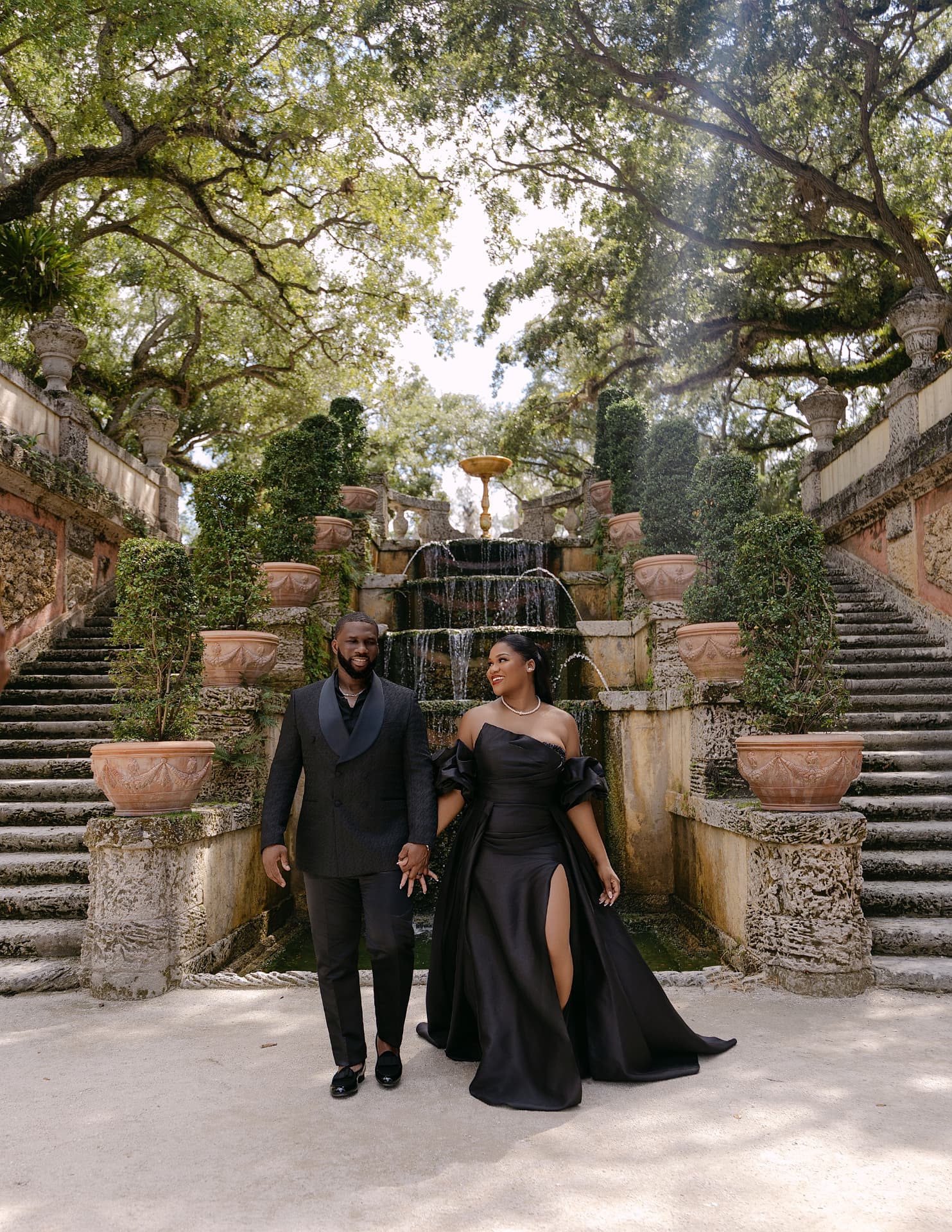 Couple walking hand in hand before a garden fountain staircase