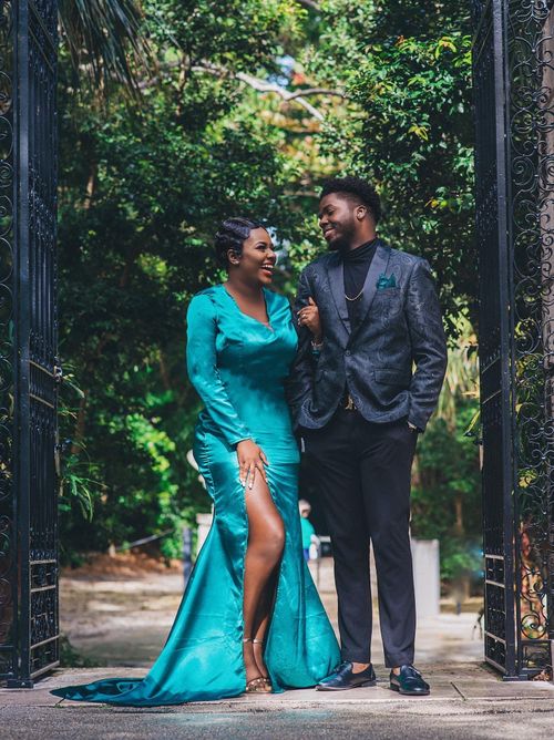 Couple laughing beneath an iron garden gate, bride in teal satin